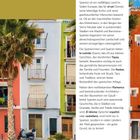 ¡Bienvenidos a España! Ein Land voller Lebensfreude. Text über Spaniens Kultur, Essen, Fiestas und Architektur. Häuser in Pastellfarben, Palmen im Vordergrund.