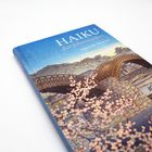 "HAIKU der Jahreszeiten, Japanisch/Deutsch". Buchcover mit Kirschblüten, einer Holzbrücke und einer Bootsfahrt.