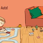 Text "Mein Auto!". Kind spielt mit rotem Auto auf Teppichstraße, neben einem Sofa mit grünem Kissen und Schaf.