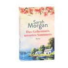 "Sarah Morgan: Das Geheimnis unseres Sommers. Roman. Illustration mit See, Boot und Häusern, umgeben von blühenden Zweigen."