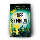 "DER SYMBIONT" in großen Buchstaben; Name des Autors: Adrian Tchaikovsky; bläuliche Landschaft mit gelben Pflanzen.