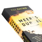 Buch mit dem Titel "MEERES DUNKEL", Autor "TILL RAETHER", gelber Himmel, Silhouetten von Bäumen, Thriller-Genre.