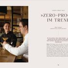 CHEFS TABLE TALK: »ZERO-PROOF« IM TREND: Zwei Männer lachen, trinken alkoholfreie Cocktails an einem Holztisch.