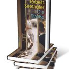 Buchtitel: "Robert Seethaler Die Straße." Eines der Bücher steht, die anderen liegen gestapelt. Cover zeigt unscharfe Straßenszene.