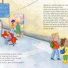 Eine elektronische Anzeige zeigt U2 und U6 mit Minutenangaben. Personen stehen in einer U-Bahn-Station nahe den Gleisen.