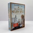 "Melodie der Neuen Welt: Auftakt in New York" von Susanne Popp. Frau auf Balkon vor historischer Stadtansicht, Spiegel-Bestseller.
