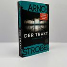 "ARNO STROBEL DER TRAKT PSYCHOTHRILLER". Oben ein leuchtender Flur mit Türen, rechts ein roter "Spiegel Bestseller"-Aufkleber.