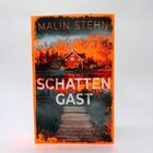 "Malin Stehn, SCHATTENGAST, KRIMINALROMAN, SCHERZ" zeigt ein Haus an einem Steg mit leuchtend orangefarbenem Hintergrund.