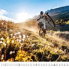 Kalender für Januar mit Datumszeilen unten. Ein Radfahrer macht ein Wheelie auf einem sonnigen Feldweg.