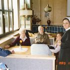 Datum „MAY 11 ‘88.“ Eine Gruppe älterer Menschen sitzt mit einer Nonne an einem Holztisch in einem hellen Raum.