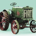 Der Text „FIAT“ ist auf einem grünen, altertümlichen Traktor zu sehen. Der Traktor hat große rote Räder.