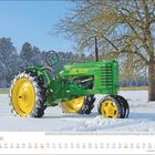 „Januar“ unten links. Grüner John Deere Traktor im Schnee, daneben ein laubloser Baum, Wald im Hintergrund.