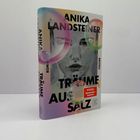 Cover von "Träume aus Salz" von Anika Landsteiner, mit Seifenblasen und einem Porträt im Hintergrund.