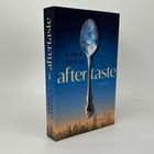 "DARIA LAVELLE aftertaste ROMAN" steht auf einem Buchcover mit einem Löffel vor einem Himmel und Stadt-Silhouette.