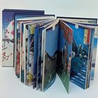 Zwei Bücher offenstehend, mit japanischen Illustrationen, zeigen Landschaftsbilder mit Bergen, Bäumen und Mond.