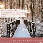 Eine verschneite Brücke führt durch einen winterlichen Wald unter einem zart strahlenden Sonnenlicht.