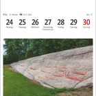 Kalenderseite mit Mai-Daten. Unten: Felsritzungen in Hornesfeltet, Norwegen. Felsen und grüne Wiese.