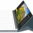 Kalender mit Terminfeldern und Spirale. Text über "Campingreisen", daneben Landschaft mit grünen Bergen und blauem Himmel.