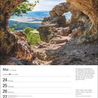 Kalenderseite: Mai-Woche 21, Zitat von Marie von Ebner-Eschenbach. Ansicht durch Felsen auf Landschaft mit Bäumen und Feldern.