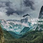 Text: "NATÜRLICHE SCHÖNHEIT." Dichte Wälder und majestätische Berggipfel unter einem bewölkten Himmel.