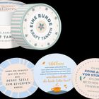 Eine runde Schachtel mit "EINE RUNDE KRAFT TANKEN" und Karten mit motivierenden Zitaten.