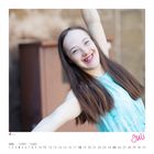 Kalenderseite für Juli mit Fokus auf eine fröhliche Frau in einem türkisfarbenen Kleid, die den Betrachter anlächelt.