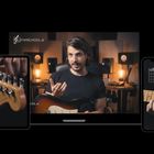 "GUITARSCHOOL.at" erscheint oben links. Ein Mann erklärt etwas mit einer Gitarre in einem Studio. Links und rechts Anzeigen.