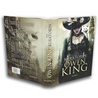 "Die Kuratorin" Owen King. Illustration: Frau mit Hut und Katze auf der Schulter, Stadt im Hintergrund.