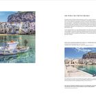 Cefalù: Ansicht eines bunten Fischerbootes vor einer Küste mit alten Gebäuden, darüber ein blauer Himmel.