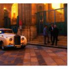 "Trapani Centro Storico" steht rechts. Ein elegantes, weißes, historisches Auto steht vor einem Gebäude, daneben drei Männer.