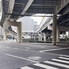 "止まれ" steht auf einem Verkehrsschild. Szene an einer mehrstöckigen Kreuzung mit Pfeilen, Hochstraßen und Gebäuden.
