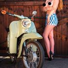 Text: Januar. Simson Schwalbe KR51/1. Frau posiert neben einem Retro-Moped vor Holztor, trägt gestreifte Shorts, schwarz zensiert.