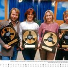 Vier Personen halten Ampex Gold Awards vor einem blauen Hintergrund. Darunter ein Kalender für Januar.