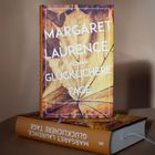 Der Text „Margaret Laurence Roman Glücklichere Tage“ befindet sich auf einem Buchcover mit einem Herbstblattmuster.