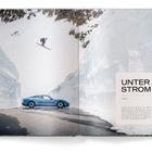 Text: "UNTER STROM KAPITEL 2." Ein blauer Sportwagen steht in einer schneebedeckten Berglandschaft, ein Skifahrer springt.