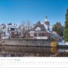 Januar 2027, Hamburg, Kalenderansicht; verschneite Backsteinhäuser am Fluss mit einem großen, grünen Baum.