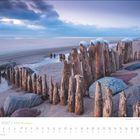 Januar 2027, Sylt, Meine Insel; Buhnenreste am Strand. Sand, Meer, bewölkter Himmel, Holzpfähle mit Schnee, große Steine.