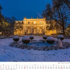 Kalenderseite Januar 2027. Winterlicher Garten mit altem Gebäude im Hintergrund, beleuchtet am Abend.
