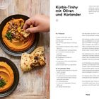"Kürbis-Tirshy mit Oliven und Koriander" und Rezeptliste. Teller mit Kürbiscreme, Oliven und Fladenbrot auf Holzuntergrund.