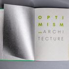 Texte: "Optimism and Architecture" in grüner und brauner Schrift, offene Buchseite, dünnes Transparentpapier.