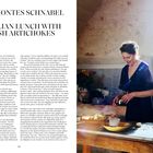 LOLA MONTES SCHNABEL  
A SICILIAN LUNCH WITH FRESH ARTICHOKES  

Eine Frau bereitet lächelnd Artischocken in einer rustikalen Küche zu. Sonnenlicht fällt durch ein Fenster.