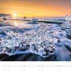 Kalender mit dem Monat Januar. Eisblöcke am Strand bei Sonnenaufgang, sanfte Wellen im Hintergrund.