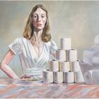 Eine Frau mit weißem Kleid steht hinter einem Pyramidenstapel aus Toilettenpapierrollen. Links liegt ein Teller mit Keksen.