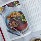 „Vegane Hähnchenkeulen mit Rosenkohl und Bratkartoffeln“. Rezeptseite offen, daneben Teller mit Braten und Gemüse.