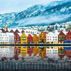 "Bryggen in Bergen" und eine Kalenderansicht. Bunte Häuser spiegeln sich im Wasser, im Hintergrund schneebedeckte Berge.