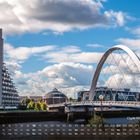 Clyde Arc - Glasgow. Kalenderdaten unten. Moderne Brücke, hoher Wohnblock links, unter bewölktem Himmel, Fluss im Vordergrund.