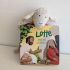 Ein Stofftier in Form eines Schafs lehnt auf einem Kinderbuch mit der Aufschrift "Lotte und das Osterfest".