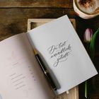 "Du bist unendlich geliebt." Links Inhaltsverzeichnis, eine Tulpe, ein Stift und ein Cappuccino auf Holz.