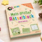 „Emmi - Mein großer Rätselblock. Ab 6 Jahren.“ Bunter Rätselblock auf einem Tisch mit Stiften, Spielwürfeln und einem Plüschtier.