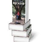 Auf einem Buchcover steht "Patrick Ryan BUCKEYE ROMAN". Ein Junge lehnt an einem Baum. Bücherstapel.